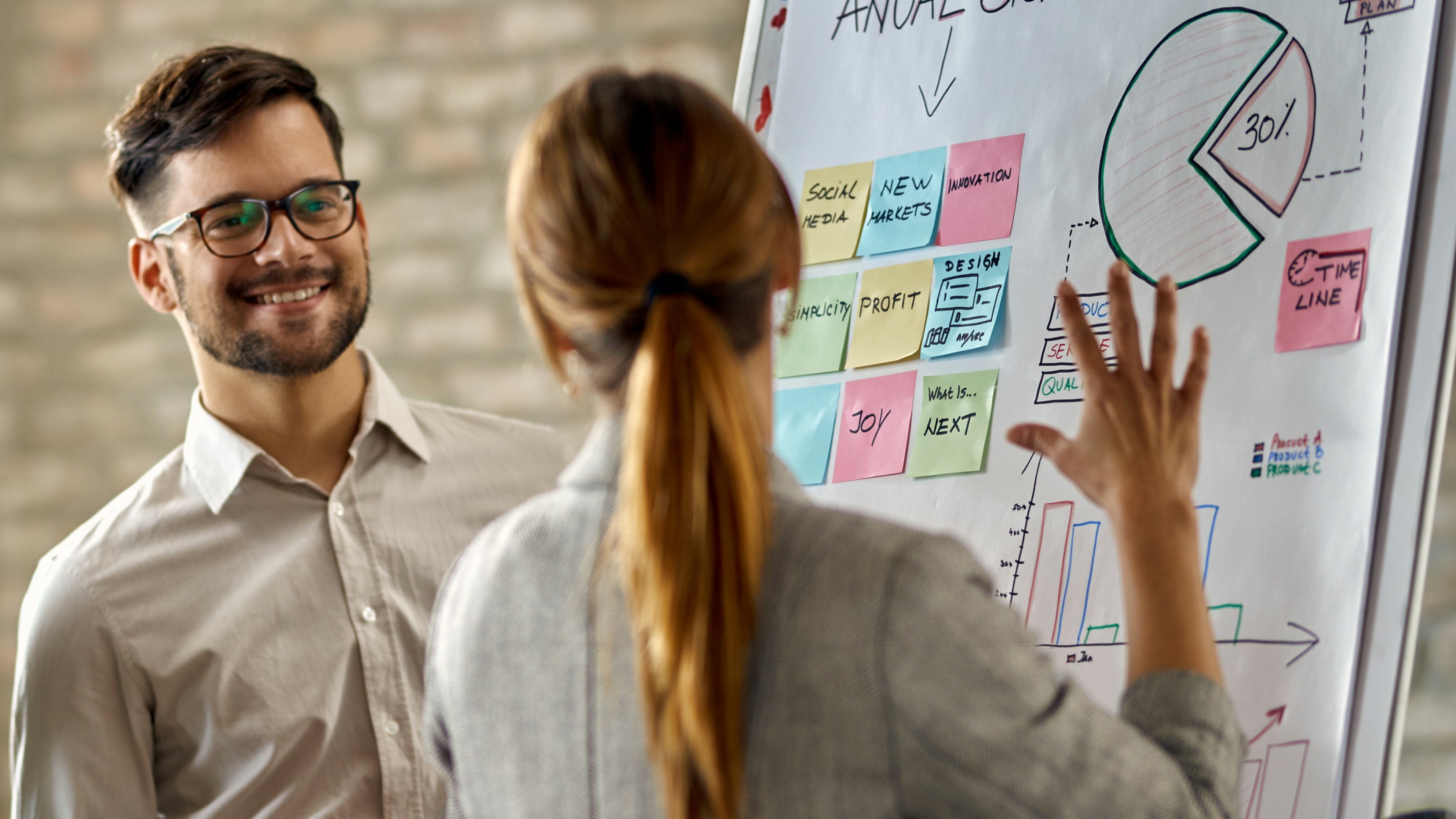 equipe-de-negocios-feliz-cooperando-enquanto-analisa-o-progresso-de-seus-negocios-no-quadro-branco-no-escritorio